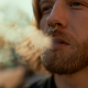Man with spectum nose ring exhaling smoke.